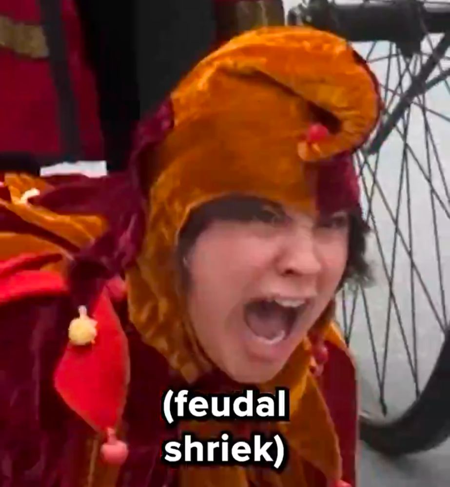 Screenshot of the video with Anna from dropout in a jester costume screaming - subtitles stating "feudal shriek"