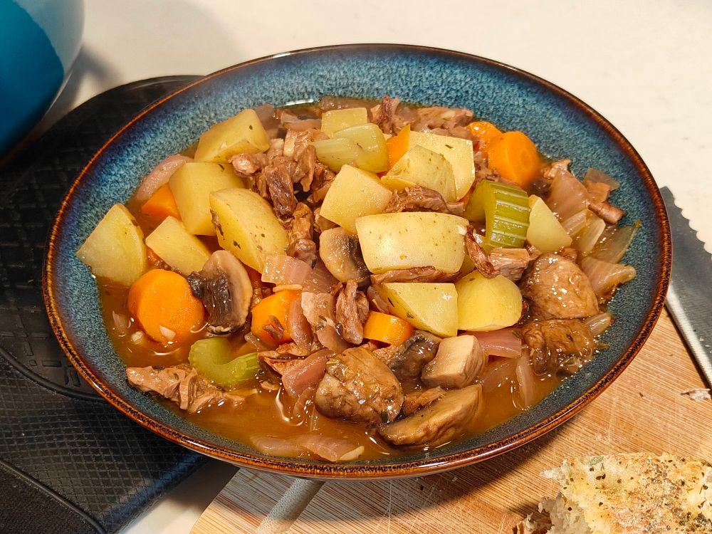a bowl of stew. plant based beef tips, potato, celery, carrot, mushroom, red onion, garlic, and veggie broth made from bouillon paste