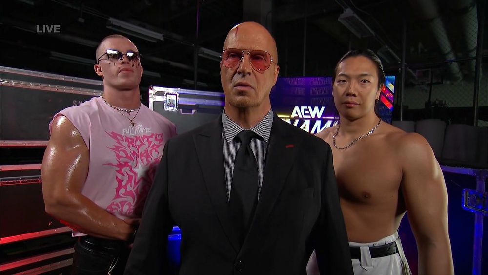 A power bottom in pink and his shirtless BF, a fashionable older man stands at the front of "The Gay Agenda".