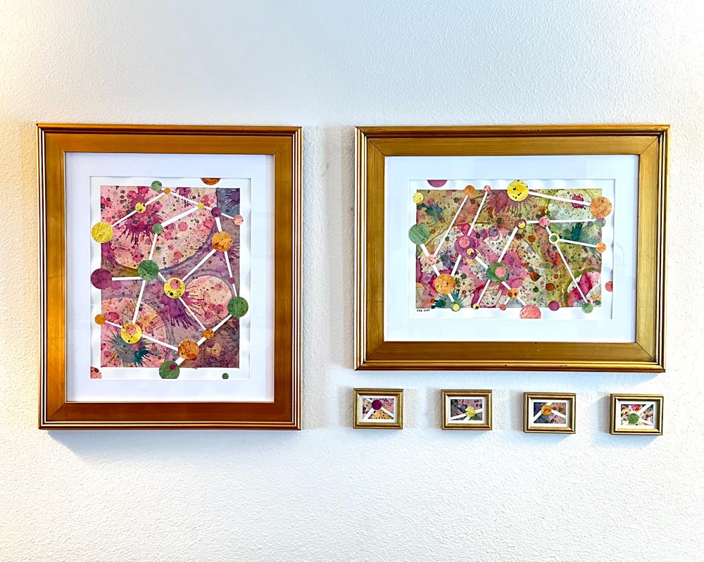 Photo of 6 framed abstract paintings. Two are quite large, and have networks of circles connected by white lines the background is a mixture of splatter paint and circles of watercolor.  Four of the framed paintings are quite small, and have just one circle in them each. 