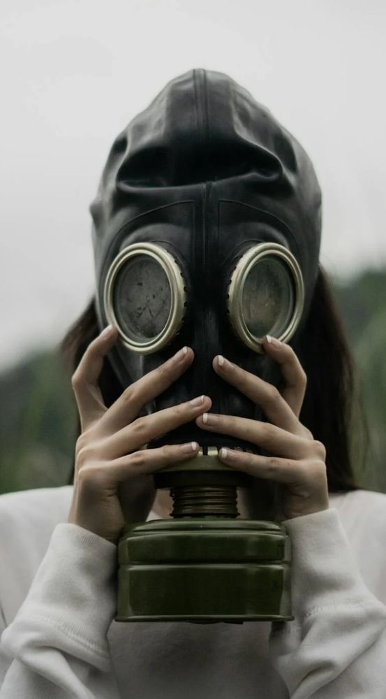 woman holding old-time gas mask in front of her face.