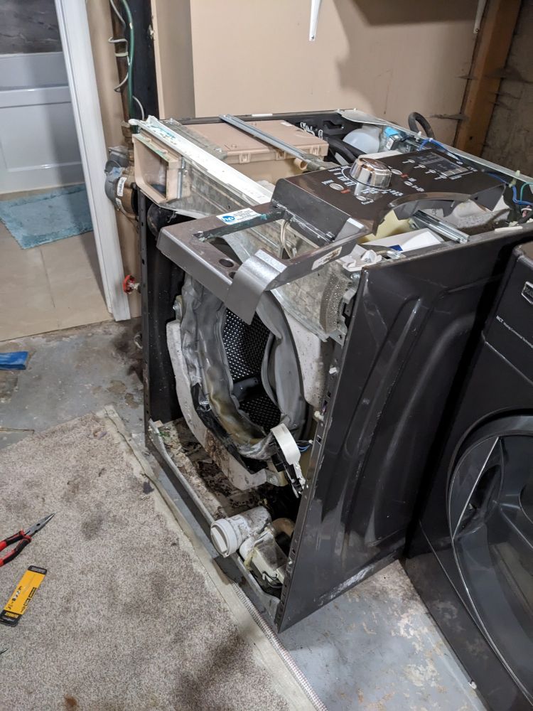 A laundry machine with the top and front panels removed.