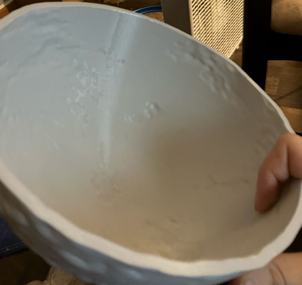 A grey plastic mold used for casting the paper. It's bowl-shaped, and has various indentations in it representing terrain.