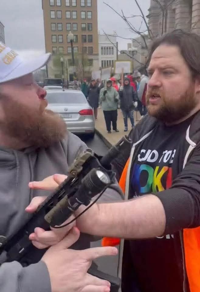 James Jordan antagonizing a protest volunteer attempting to stop him. Here you can see the volunteer pushing away the rifle Jordan had been brandishing. 