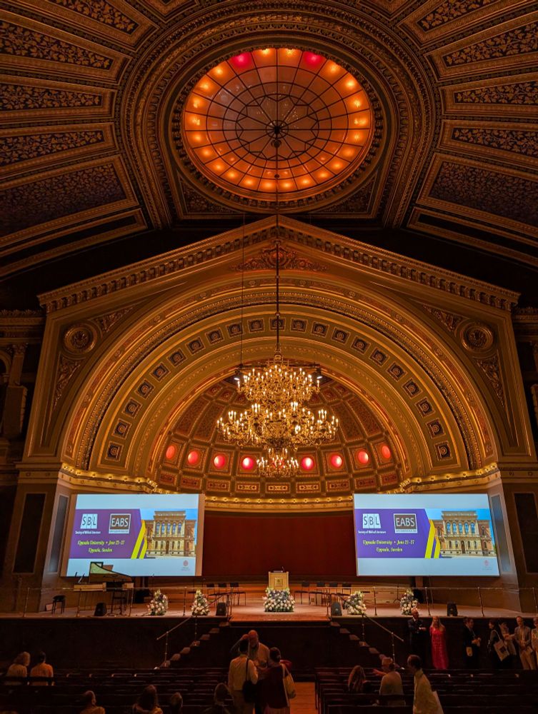 Picture into the main hall of Uppsala university. On the stage there is the starting page of a PowerPoint telling us that we are at an event of SBL and EABS. 
