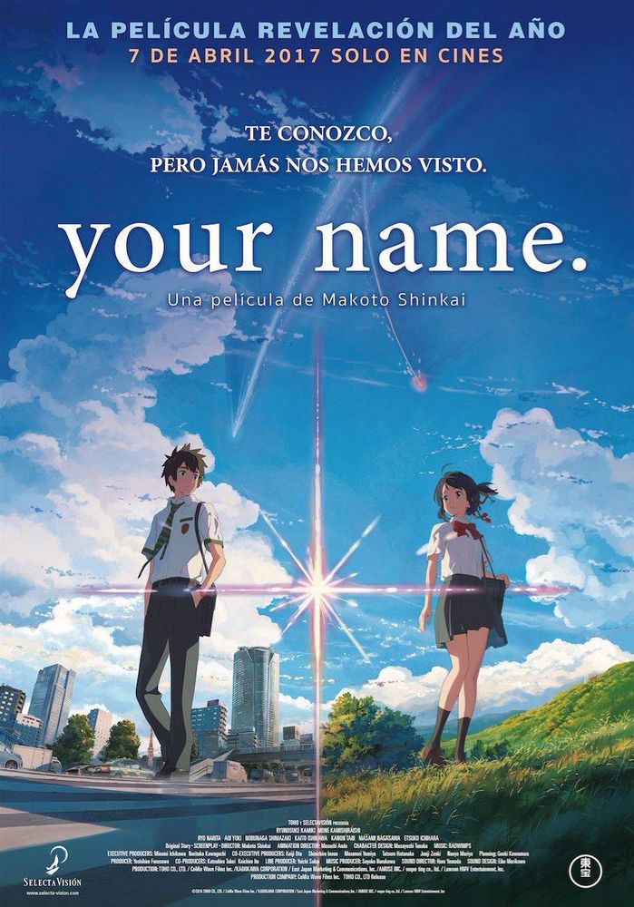 Poster for the movie Your Name. In the middle is a flash of light separating the two main characters, two high school students. On the left is a boy named Taki, with Tokyo appearing in the background. On the right is a girl named Mitsuha, in the middle of a grassy meadow. They both look in the general direction of the other, though it doesn’t seem as though they look directly at each other. The upper portion of the poster is primarily covered in a blue sky and clouds, though there’s also a comet flying by. It splits in two, with one trail heading towards Taki and the other towards Mitsuha. The movie title appears at the top of the poster.