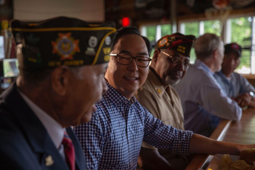 Asian man at a bar with veterans sitting next to him on either side in conversation