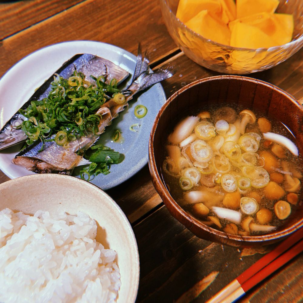 食卓の写真 手前に白米ときのこの味噌汁、奥にさんまの酒蒸しと柿