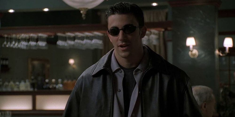 Jackie Aprile Jr. wearing sunglasses in Vesuvio with a coat and half buttoned shirt