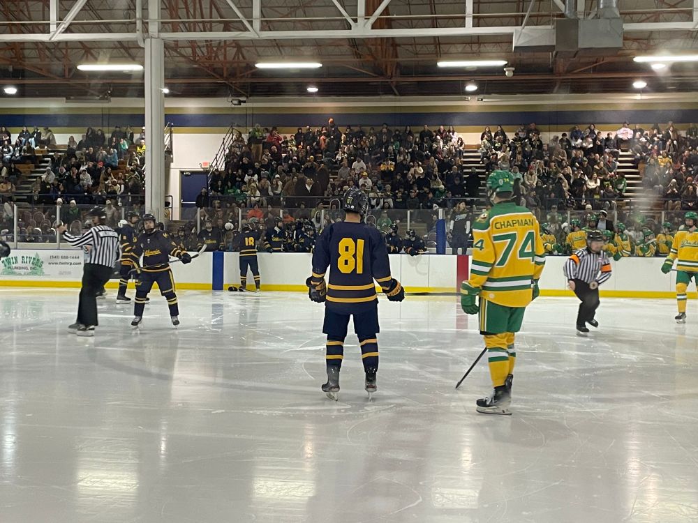 Oregon Ducks vs California Golden Bears in ACHA Hockey. The Ducks are wearing gold jerseys with green trim, and Cal is wearing their navy blue jerseys with gold trim.