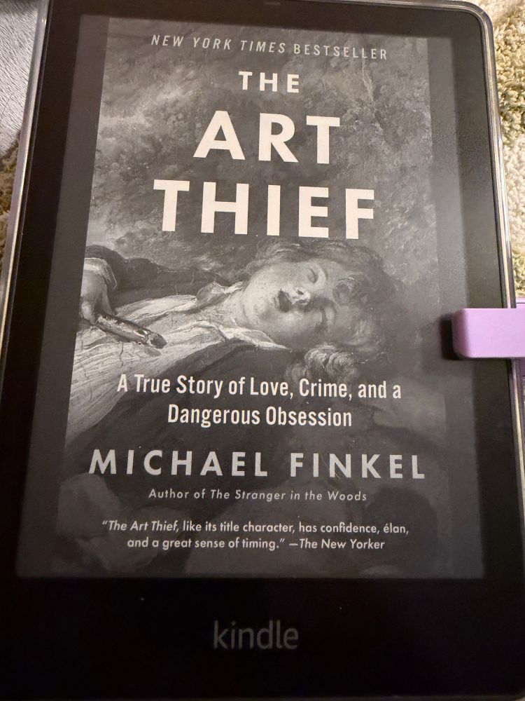 The cover of The Art Thief: A True Story of Love, Crime, and a Dangerous Obsession by Michael Finley on an Kindle Paperwhite with a purple page turner clipped to the side. 