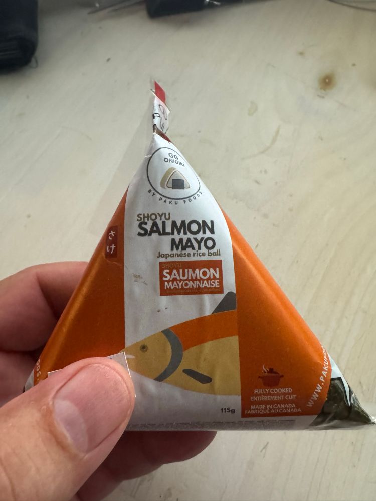 Onigiri package unopened. A triangular package with (in this case) salmon mayo in a rice ball wrapped in dried seaweed. 