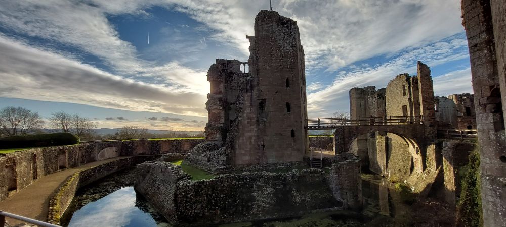 A view over the moat into the sun (hidden behind a tower) with interesting clouds.