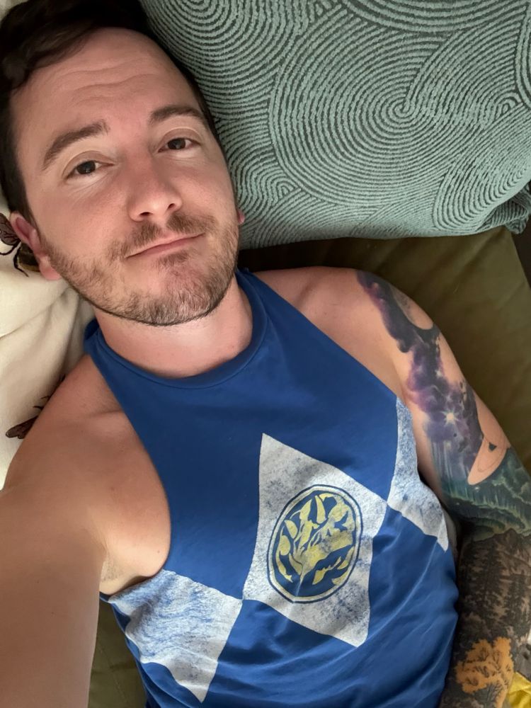 Josh laying on the couch wearing a cutoff blue power ranger shirt