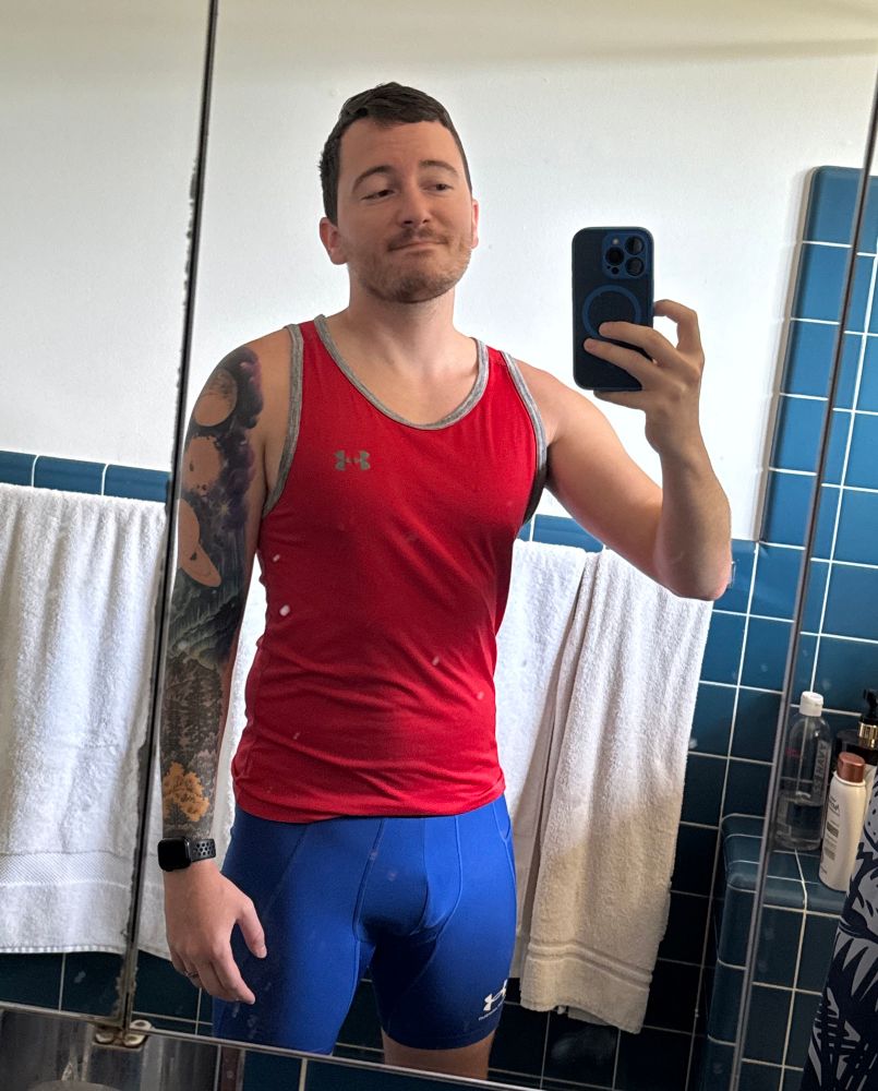 Josh wearing a red Under Armour tank top and blue Under Armour compression shorts.