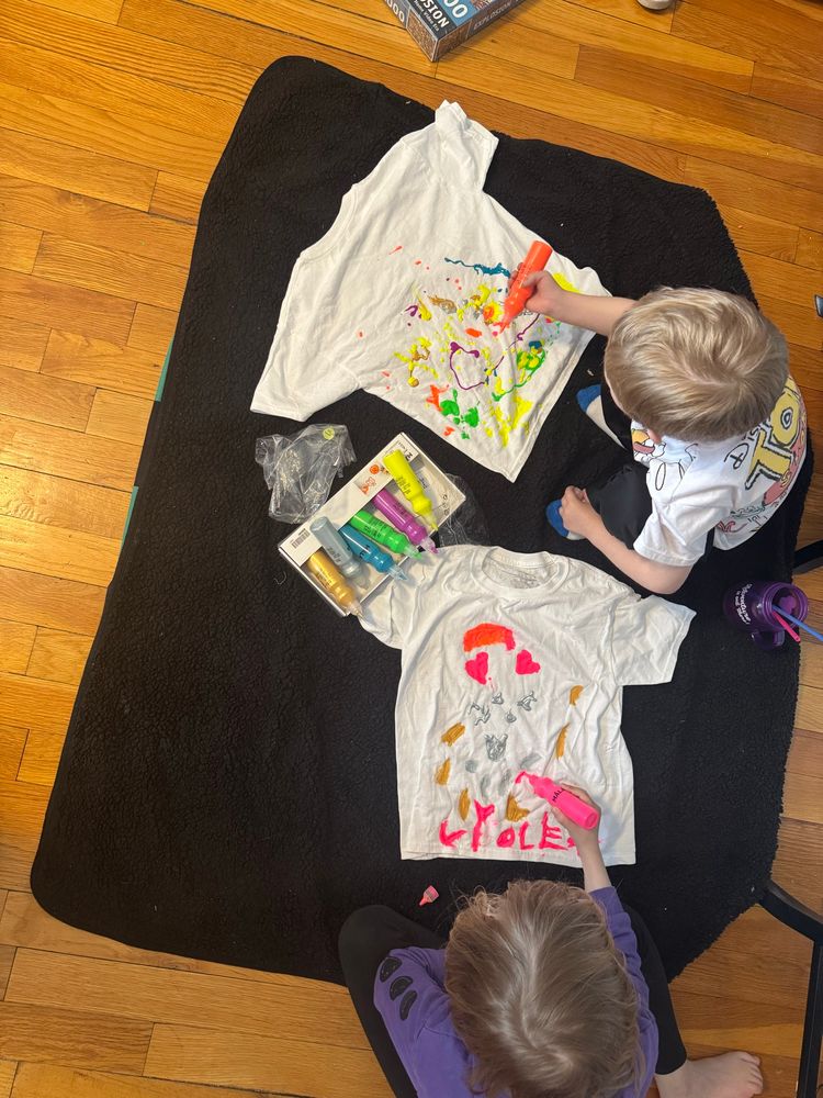 Two kids playing with painting on tee shirts 