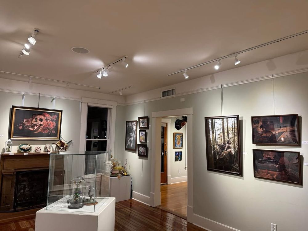 A photo of the room where my three pieces of art were featured for the art show. Shrike is over the fireplace mantle on the right side in a large print, Devils eye and Charlatan are on the left in slightly smaller prints.

Other pieces of are also arranged around the room. 