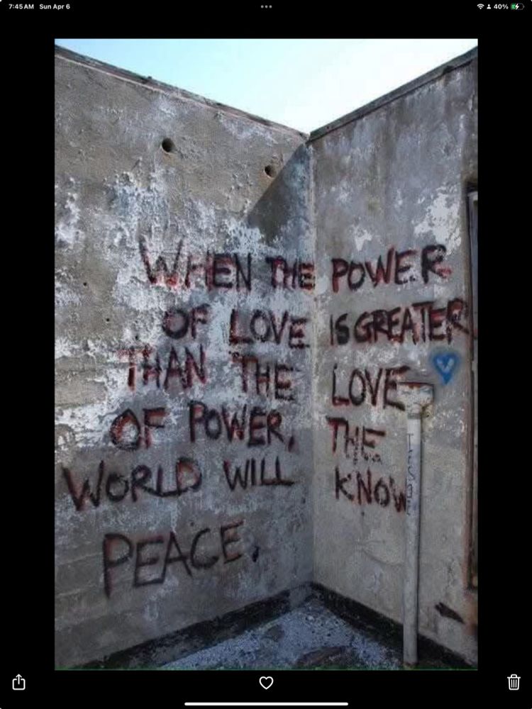 Red letters on a cement wall, "When the power of love overcomes the love of power, the world will know peace," is attributed to Jimi Hendrix.
