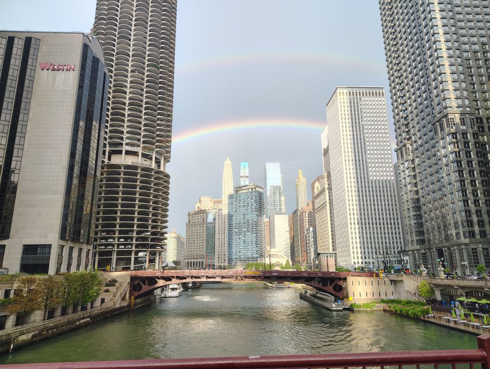 Picture of the Chicago River downtown with a rainbow over the buildings to the east of the Clark Street bridge.