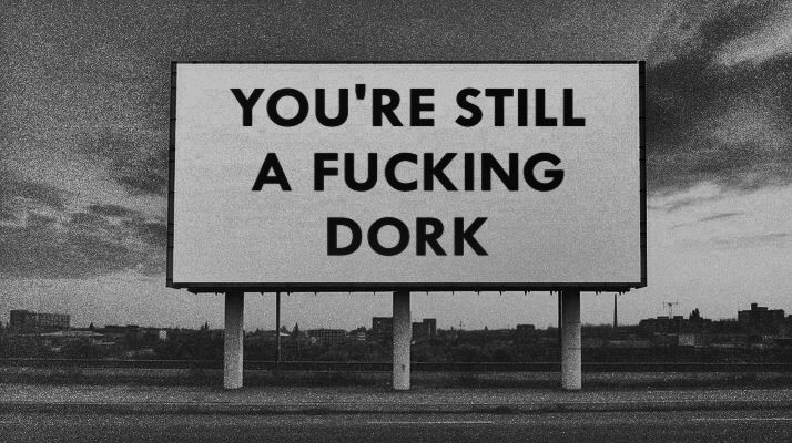 A billboard in black and white that says "You're still a fucking dork."