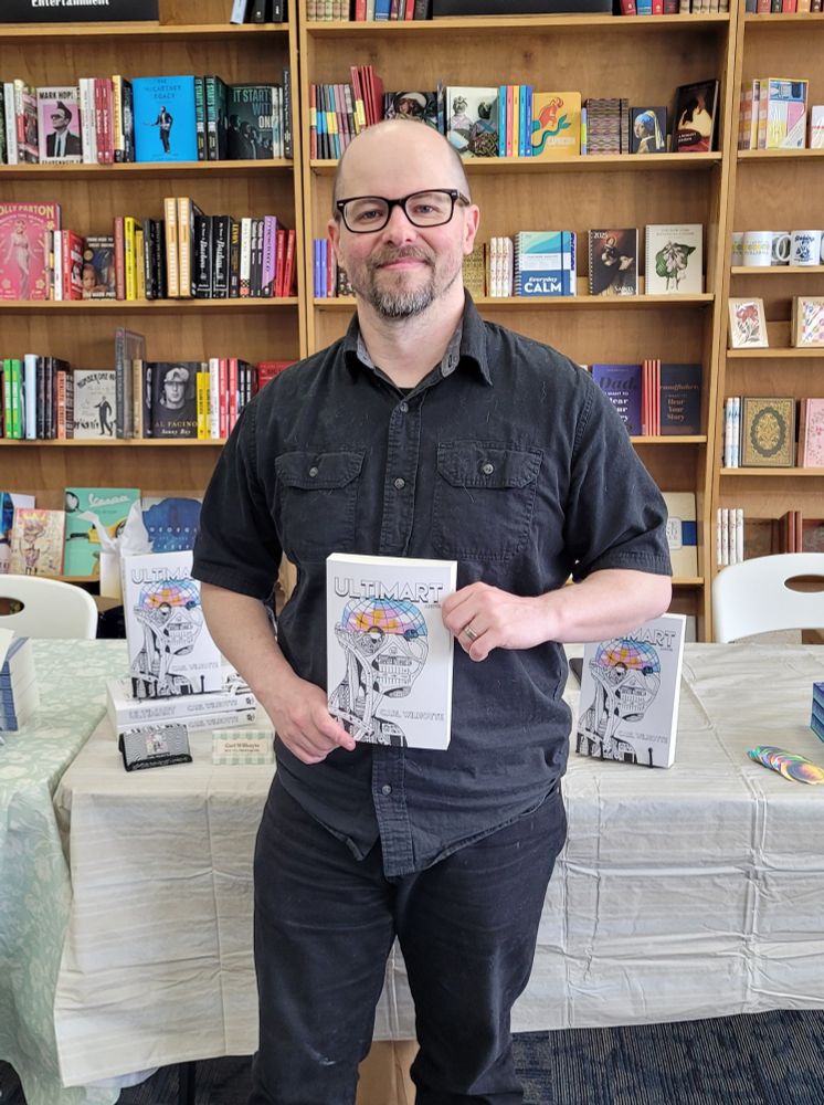 Man standing holding book in front of bookshelves
