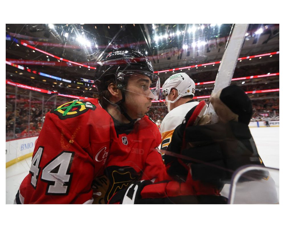 Apr 6, 2025; Chicago, Illinois, USA; Pittsburgh Penguins center Noel Acciari (55) checks Chicago Blackhawks defenseman Wyatt Kaiser (44) against the glass during the first period at United Center. Mandatory Credit: Talia Sprague-Imagn Images