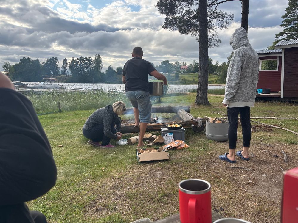 Mehrere Personen kochen Essen auf einem Feuer.