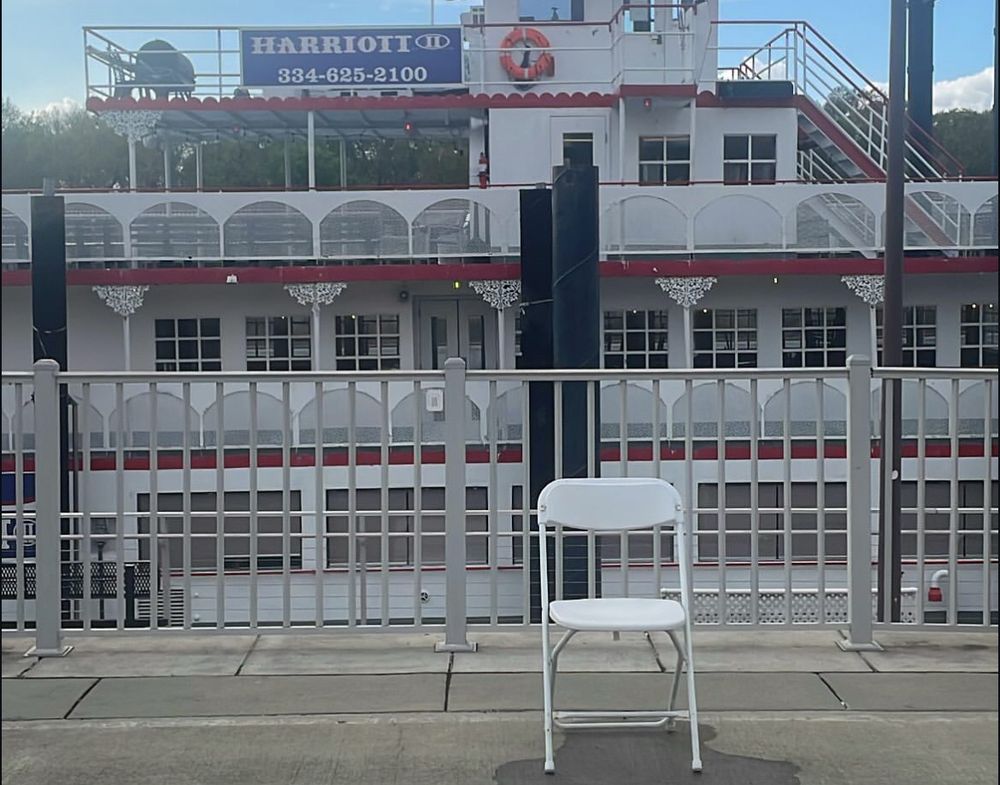 Picture of the white chair on the Montgomery, Alabama riverfront in front of the Harriott riverboat.