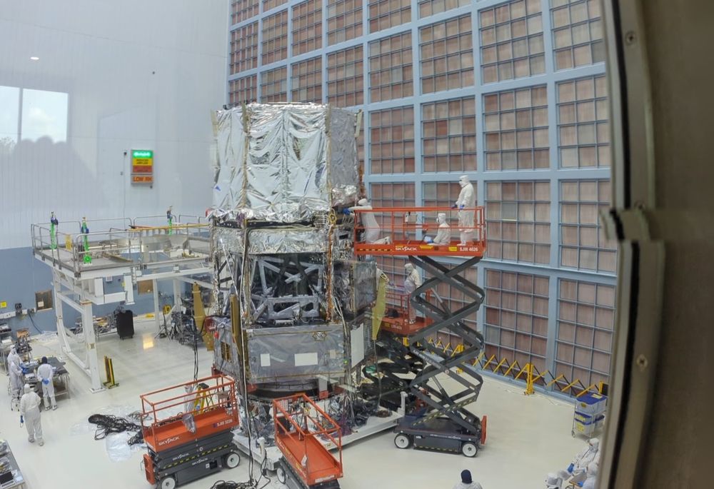 Four men on a scissor lift, working on the wiring of the Nancy Grace Roman telescope in the assembly bay at NASA GSFC.