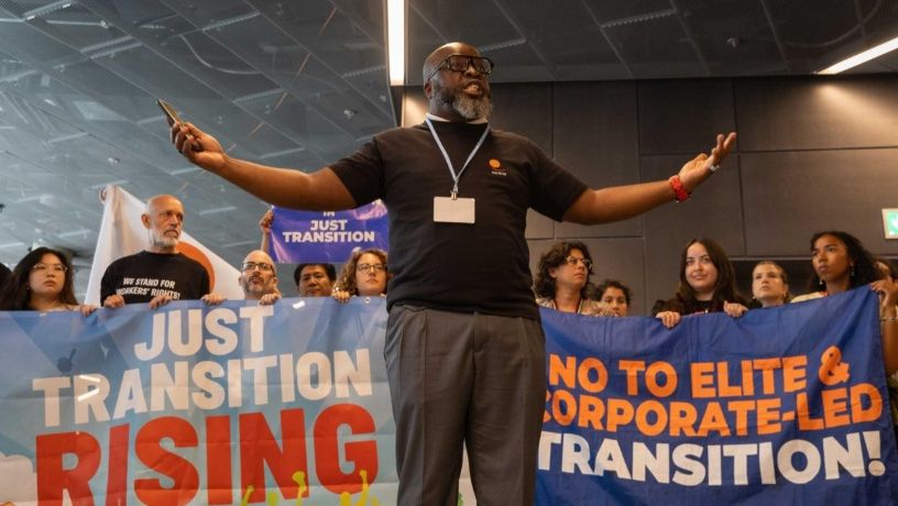 A man standing in front of banners calling for a just transition in Bonn, Germany. 