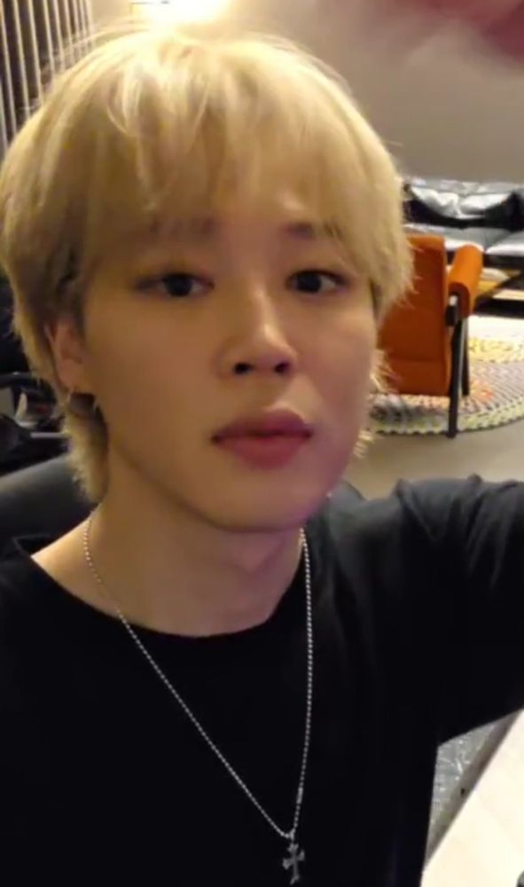 Jimin with blond hair wearing a black shirt and a silver necklace 
