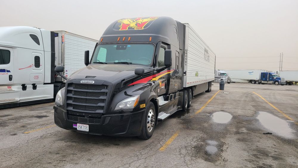 A black semi truck has a thin brown layer of dust coating it. 
