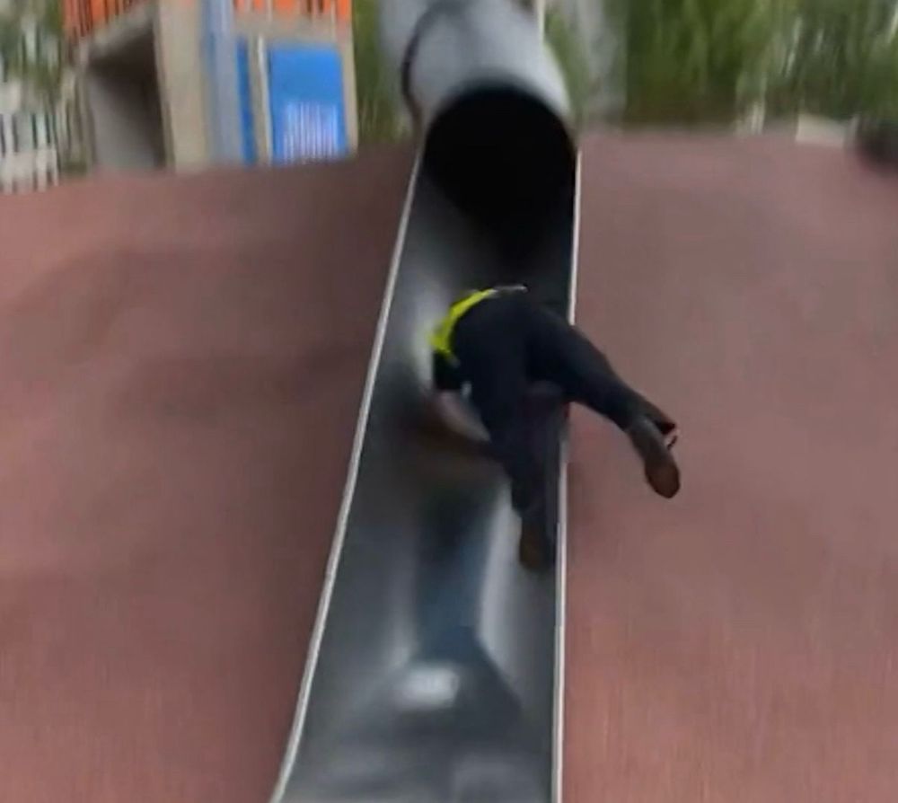 Screenshot of a policeman falling down a silver metal slide face-first.