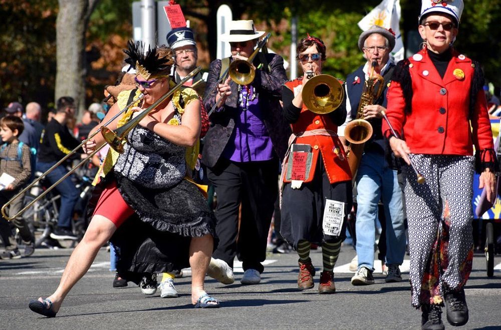 Members of the Leftist Marching Band, dressed in colorful garb and playing their instruments while marching.