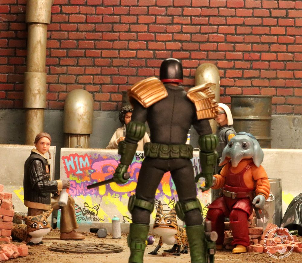 Judge Dredd stands in front of the kids holding his daystick. He has caught the Skeleton Crew doing graffiti on a concrete barrier. Dredd has no qualms about arresting juves. 