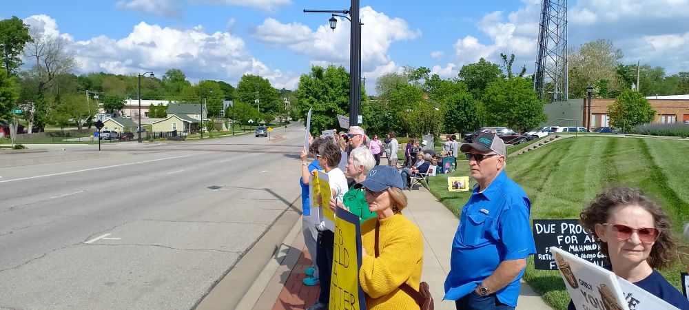 A crowd of people along the street attending the May Day rally in Olathe Kansas.
