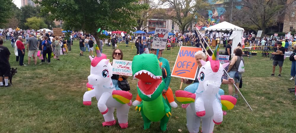 Costumes of people riding unicorns and a t-rex.