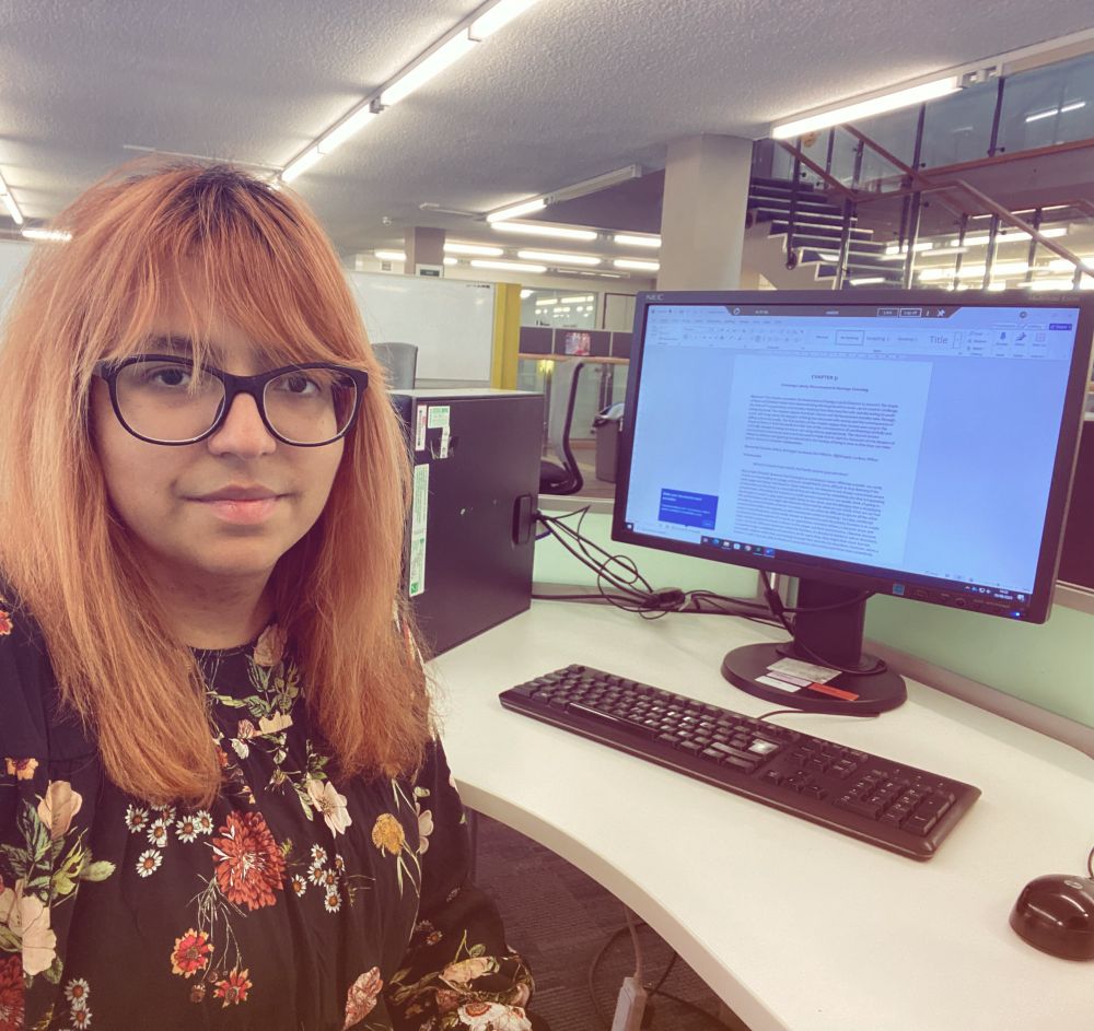 Picture of me sitting at a desk in the library in front of a computer.