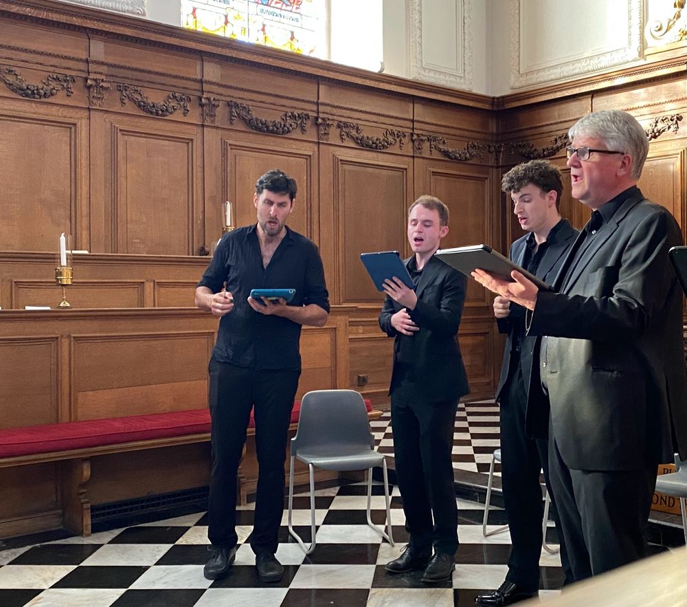 A group of four men singing in a chapel.