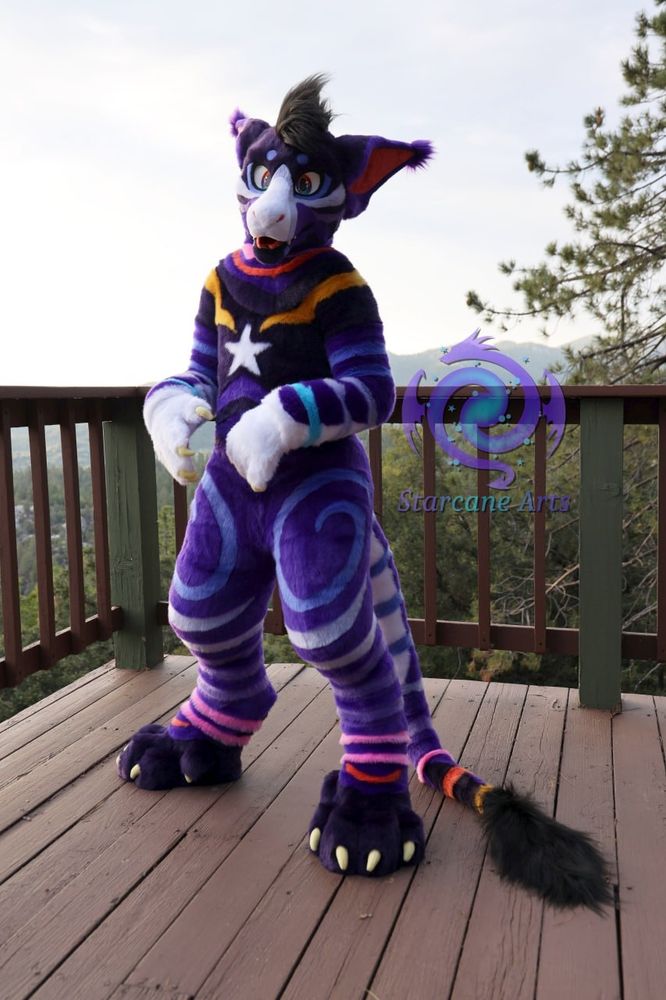 A primarily purple vernid fullsuiter is seen standing on a wooden deck overlooking a mountain landscape.