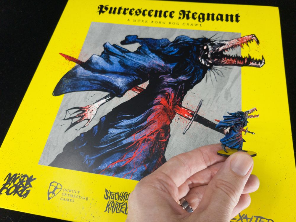 Painted mini being held up in front of the Putrescence Regnant album cover it's based on.