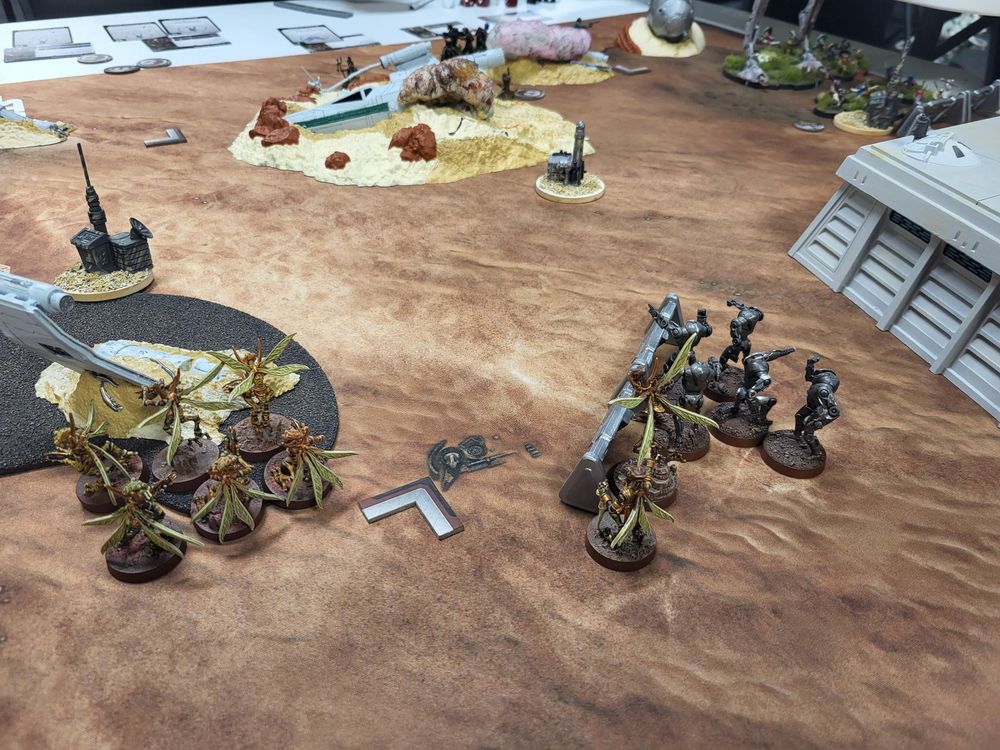 Star Wars Legion tabletop minis game with just-deployed Geonosians in the foreground and distant ewoks hiding behind a crashed X-wing.
