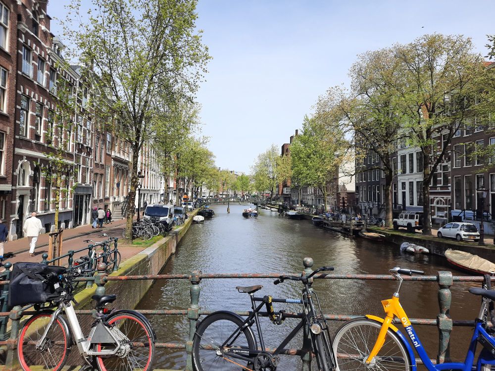A photo of a canal in Amsterdam with bikes chained to the side