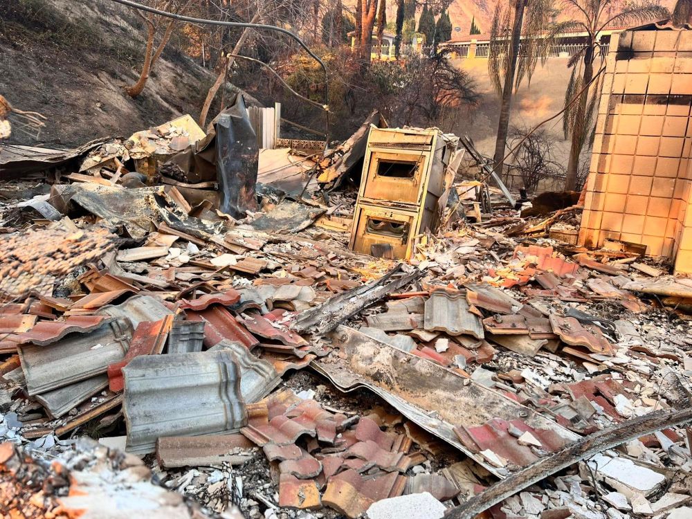 A photo from the burnt remains of the Zooh Corner residence. There is piles of roof tiles atop of the burnt remnants of the house 
