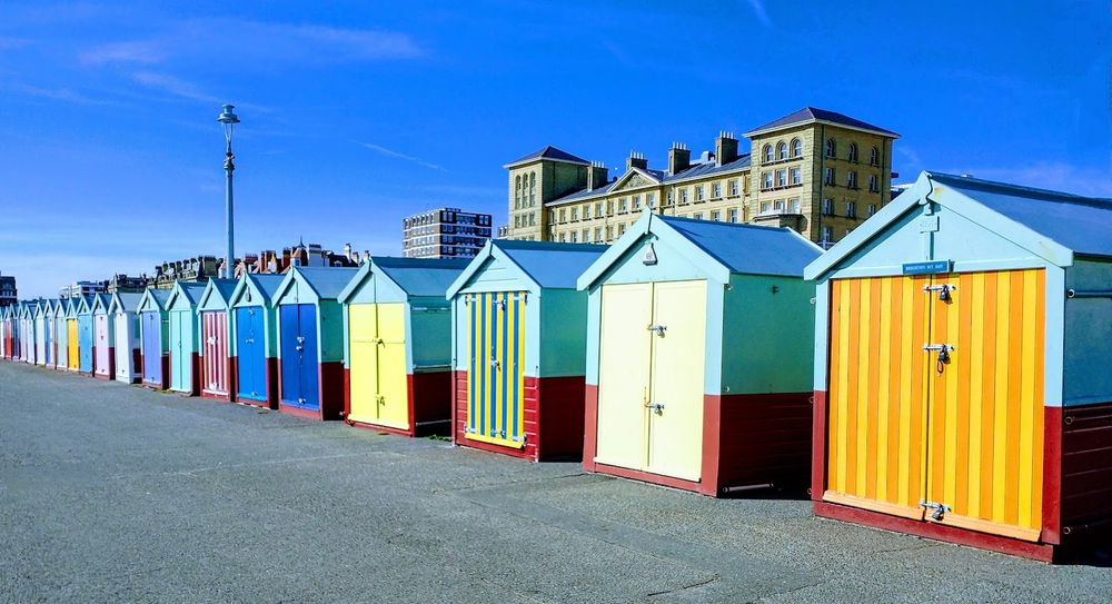 Brightly colored beach huts standing in a row along the shore.