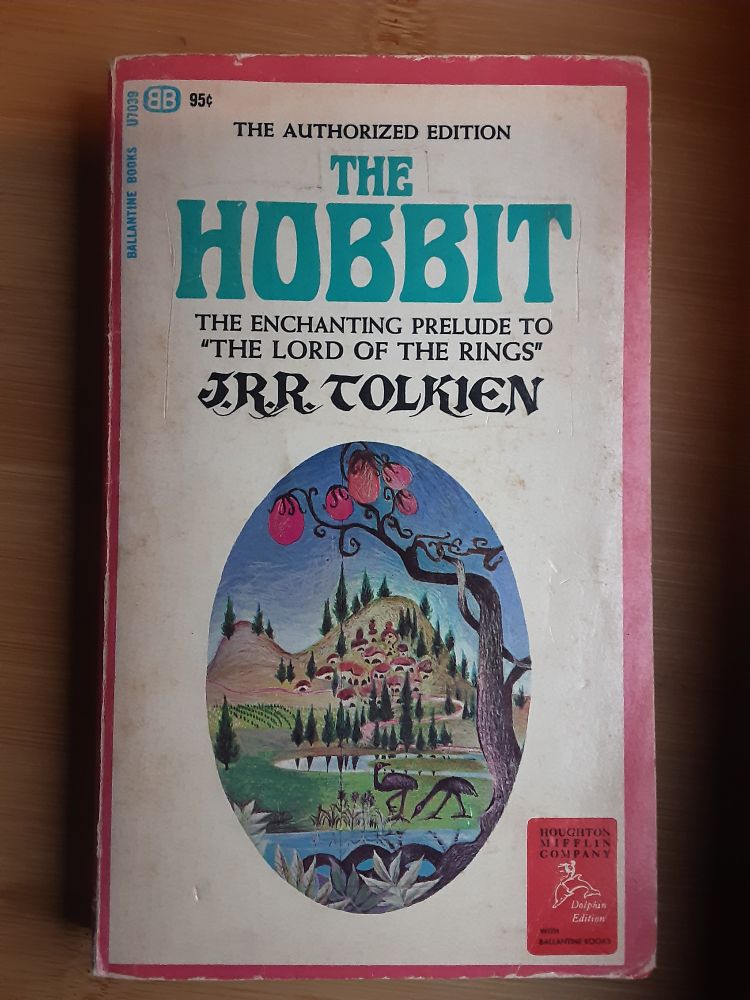 A paperback: The Hobbit, by JRR Tolkein. With trippy looking trees and birds in foreground and a village on a hill in background, all very 1960s.