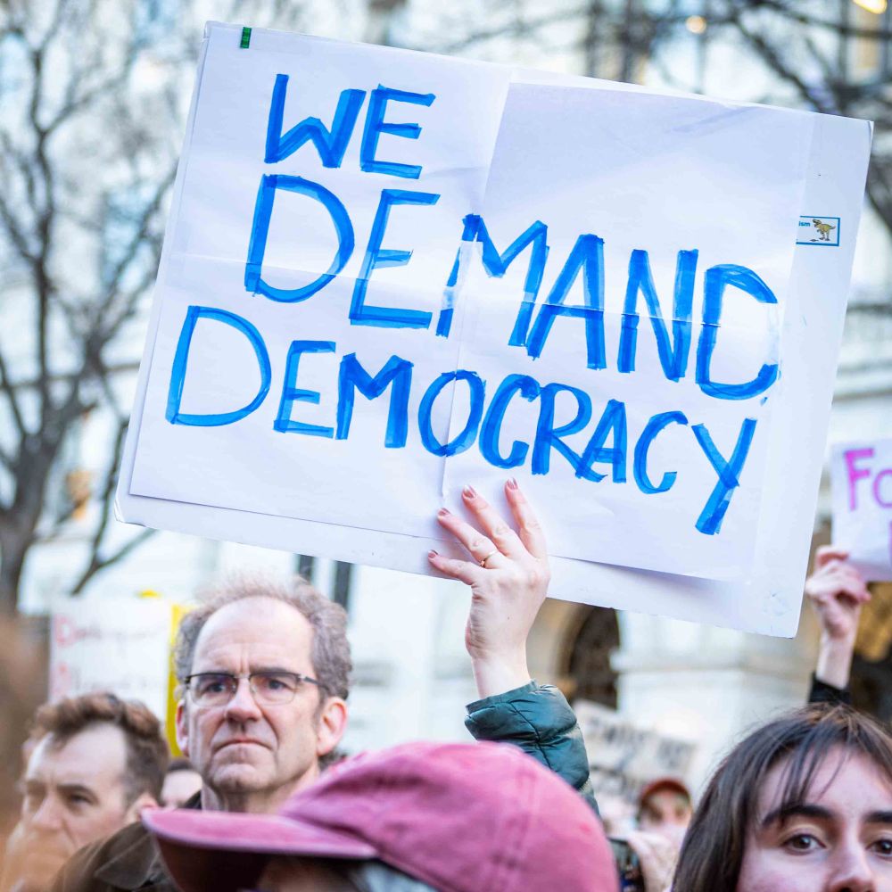 Man holding a sign “We demand democracy.”