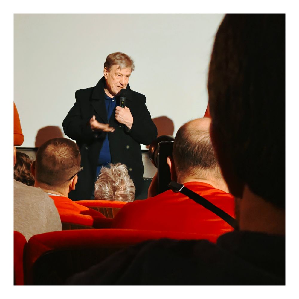 Le réalisateur John McTiernan s’exprime devant les spectateurs d’une salle de cinéma.