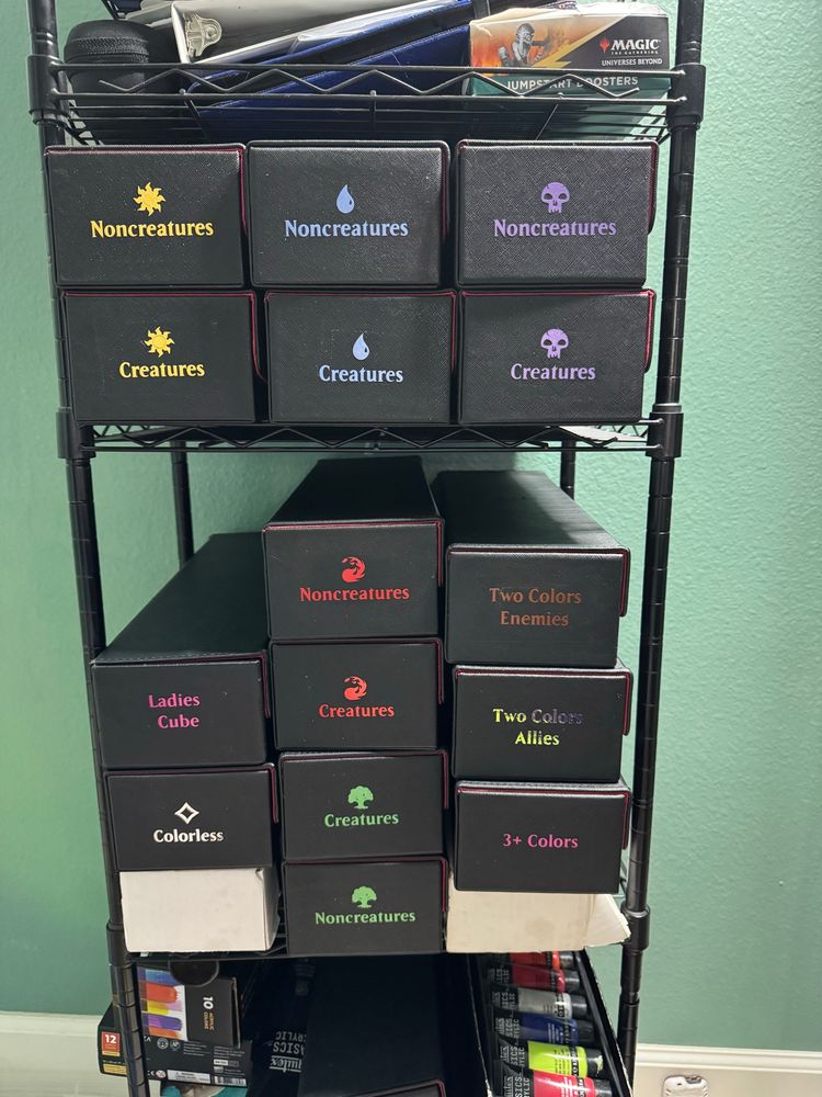 Shelf with boxes of cards labeled with mana symbols.