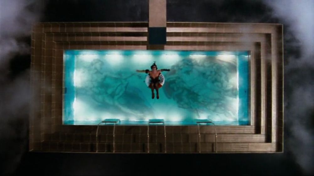 Frank-N-Furter (Tim Curry) flutua em uma boia no meio de uma piscina, enevoada nas extremidades da tela, cujo fundo é uma representação do famoso afresco "A Criação de Adão" de Michelangelo, finalizado pelos idos de 1511.